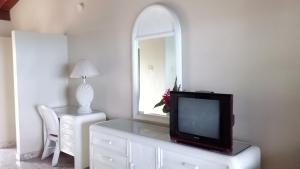 a living room with a tv and a mirror at Silver Seas Hotel in Ocho Rios