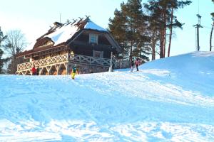 a log cabin on a snow covered slope with people in front at Vēju ritmi in Labvārži
