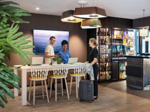 a group of people standing around a bar with laptops at Novotel Rennes Alma in Rennes