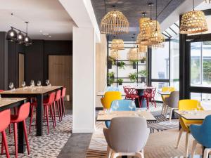 a restaurant with tables and chairs and chandeliers at Novotel Rennes Alma in Rennes
