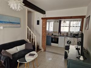 a living room with a couch and a kitchen at Romance en Baie de Somme in Saint-Valéry-sur-Somme