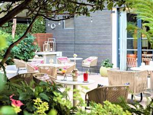 un patio al aire libre con mesas, sillas y plantas en Hotel Croisette Beach Cannes - Mgallery en Cannes