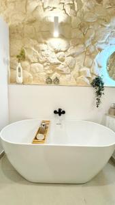 a white bath tub in a bathroom with a stone wall at MCC St Rita in Il-Furjana +24 photos