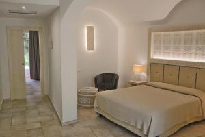 ein Schlafzimmer mit einem Bett und einem Stuhl in der Unterkunft Corte Bianca - Adults Only & SPA - Bovis Hotels in Cardedu