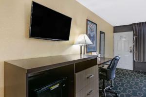 um quarto de hotel com uma secretária e uma televisão de ecrã plano em Clarion Inn International Drive em Orlando