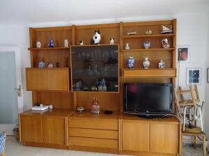 a entertainment center with a television on a wooden entertainment cabinet at brisa mar in San Pol de Mar