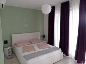a bedroom with a white bed with purple curtains at Ana Rooms in Krk