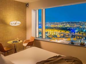 a bedroom with a view of a city from a window at Too Hotel Paris - MGallery in Paris