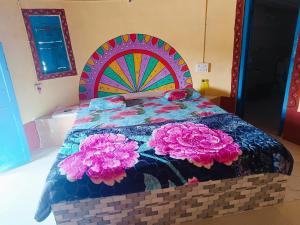 a bed with a colorful bedspread with flowers on it at Rann Kutch Resort in Dhordo