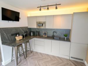 a kitchen with white cabinets and a black counter top at Valley Lodge 4 - North Wales Eco Lodges in Ruthin