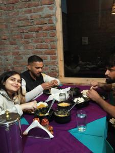 un grupo de personas sentadas en una mesa comiendo comida en The Riverbank Nest, en Jibhi