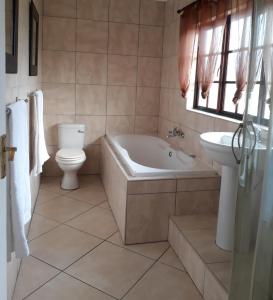 a bathroom with a tub and a toilet and a sink at Mountain View Holiday Home in Franskraal