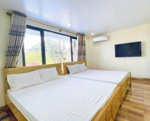 a bedroom with two beds and a large window at Gem Hostel in Cat Ba