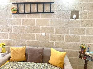 un divano con cuscini gialli di fronte a un muro di mattoni di Antica Pietra a Polignano a Mare