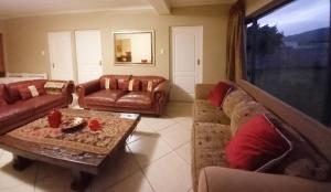 a living room with couches and a table and a window at Mountain View Holiday Home in Franskraal