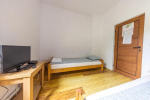 a small room with a bed and a desk with a television at Gurasada Park Hostel in Gothatea