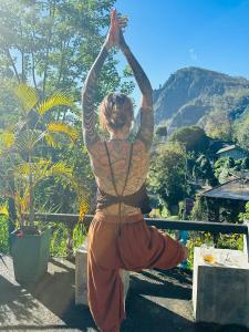 a woman doing a yoga pose in front of a mountain at Rock View Hostel Ella in Ella