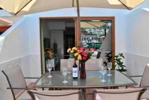 a glass table with a vase of flowers and wine glasses at Montecarlo 35 or 45 first row with air conditioning & WI-FI & sound insulation in Puerto Rico de Gran Canaria