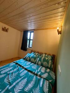 a bedroom with a bed with a blue comforter and a window at Big stone in Dilijan