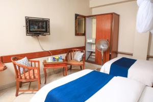 a hotel room with two beds and a television at Paris Hotel in Nairobi