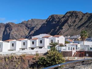 a row of white houses with mountains in the background at El Marques Resort Townhouse in Puerto de Santiago