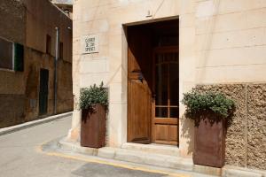 a building with a wooden door and two plants at S'Hotelet de Santanyi in Santanyi