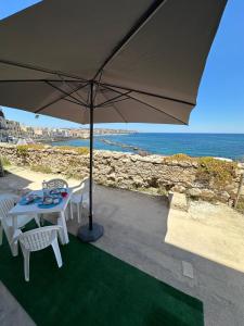 - une table et des chaises sous un parasol près de l'océan dans l'établissement Terrace on the sea, à Syracuse