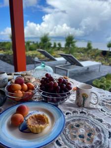 a table with a plate of fruit and a cup of coffee at Casa Baleia Laranja Ocean-Front in Cabeço Chão