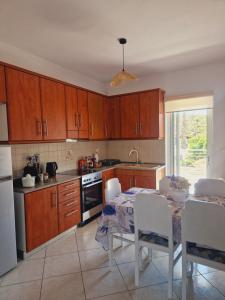 a kitchen with wooden cabinets and a table with chairs at Comfortable Apartment close to Rafina port in Rafina