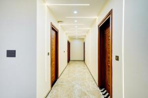 a corridor with white walls and wooden doors at Hotel O DEVOM INN in Greater Noida