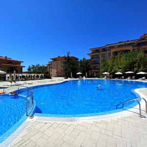 a large blue swimming pool with chairs and umbrellas at Star Dreams Apartment with Glass Veranda in Sveti Vlas