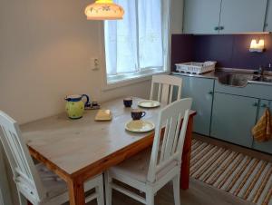 a kitchen with a wooden table and white chairs at Kongsfjord Holiday Home in Kongsfjord