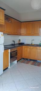 a kitchen with wooden cabinets and a white refrigerator at Liv Skyline Apartment in Sarandë