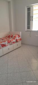 a bed in a white room with a window at Liv Skyline Apartment in Sarandë