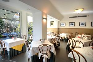 ein Restaurant mit weißen Tischen und Stühlen und einem Fenster in der Unterkunft Hotel Ghironi in La Spezia