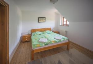 a bedroom with a bed with a green comforter at Juhfark Fogadó és Borház in Balatoncsicsó