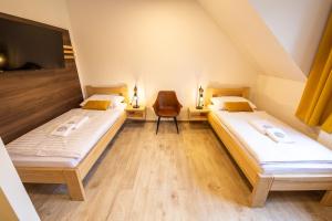 two beds in a attic room with a chair at Penzión Esprit in Sučany +118 photos
