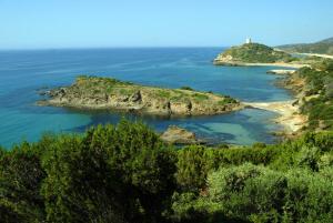 an island in the ocean with a lighthouse in the distance at Hotel Spartivento in Chia