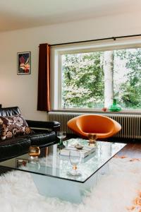 een woonkamer met een bank en een glazen tafel bij Bungalowvilla Robin Hill, met bostuin & design interieur in Haelen +38 foto's