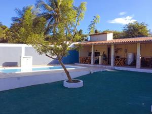 a house with a palm tree in front of a swimming pool at Pousada Vista Verde in Paracuru