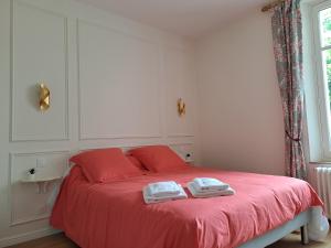 ein Schlafzimmer mit einem roten Bett mit zwei Handtüchern darauf in der Unterkunft Le Relais du Golf- Château de la Touche in Ballan-Miré