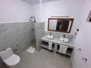 ein Bad mit einem WC, 2 Waschbecken und einem Spiegel in der Unterkunft Nungwi Beach Front Ex Sunrise Beach Nungwi in Nungwi