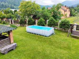a swimming pool in a yard with two benches at Шум лісу in Tatariv