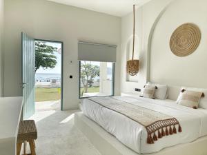 een witte slaapkamer met een groot bed en een groot raam bij Kacchapa Beach Resort and Restaurant in Sekongkang