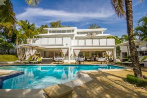 a large white house with a swimming pool and palm trees at Casa Veintiuno in Sosúa