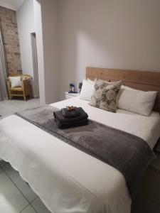 a large white bed with a black tray on it at Stay@Opstal in Pretoria