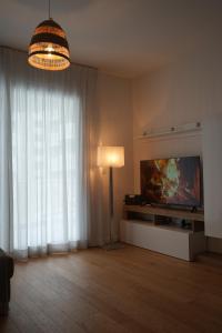 uma sala de estar com uma televisão de ecrã plano e um candeeiro em La Mia Casa Romana em Roma