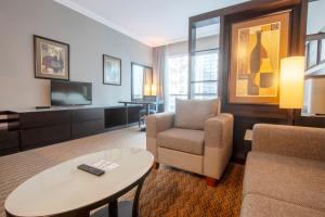 - un salon avec un canapé, une chaise et une télévision dans l'établissement Al Manzel Hotel Apartments, à Abu Dhabi