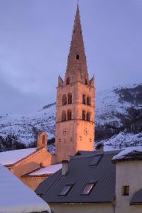 een klokkentoren bovenop een gebouw met sneeuw bij Alliey & Spa Piscine Appart-hôtel Serre chevalier in Le Monêtier-les-Bains