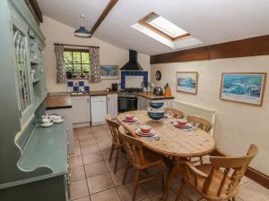 a kitchen with a wooden table and chairs in a kitchen at Preseli Hills Cottage in Fishguard +13 photos